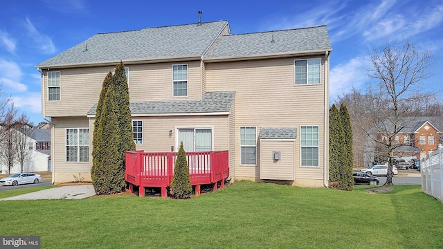 back of property with a shingled roof, a lawn, and a wooden deck