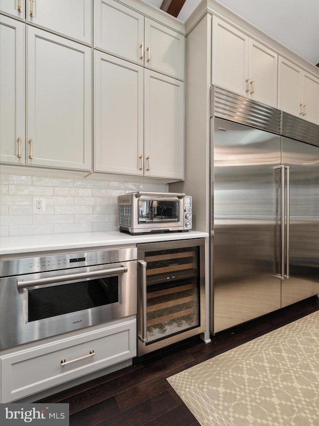 kitchen featuring a toaster, beverage cooler, tasteful backsplash, appliances with stainless steel finishes, and light countertops