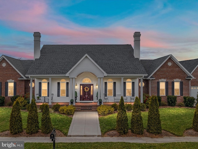 view of front of home featuring brick siding, a lawn, a chimney, and stucco siding