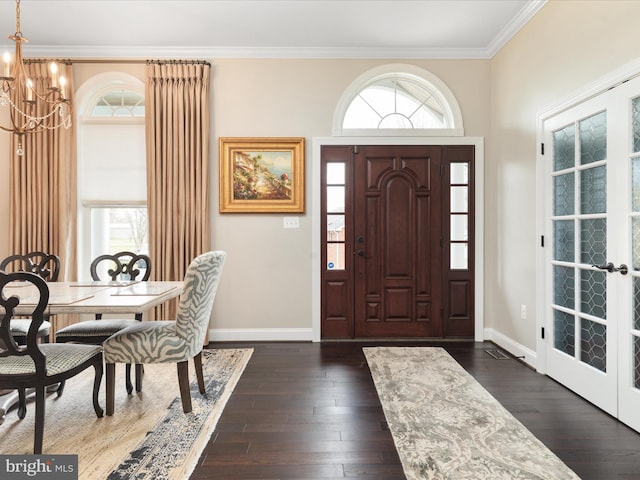 foyer entrance with crown molding, a notable chandelier, baseboards, and dark wood-style flooring