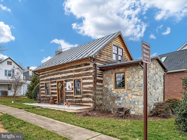 view of front of property with metal roof, a front lawn, a standing seam roof, and a chimney