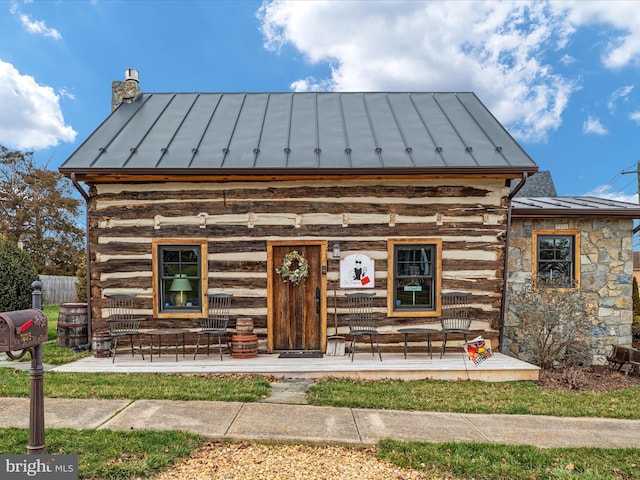 view of front of house with metal roof, log exterior, and a standing seam roof