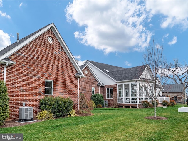 exterior space featuring a yard, central AC unit, a sunroom, and brick siding