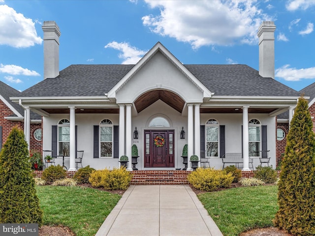 property entrance with covered porch, roof with shingles, a chimney, and stucco siding