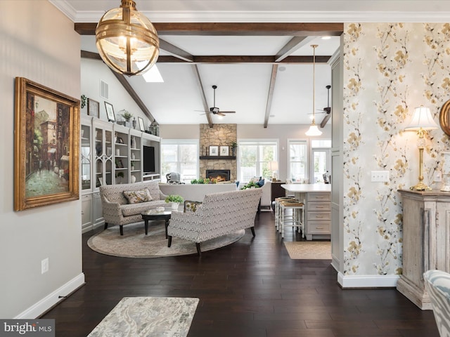 living area featuring baseboards, dark wood-style floors, ceiling fan, beamed ceiling, and a fireplace