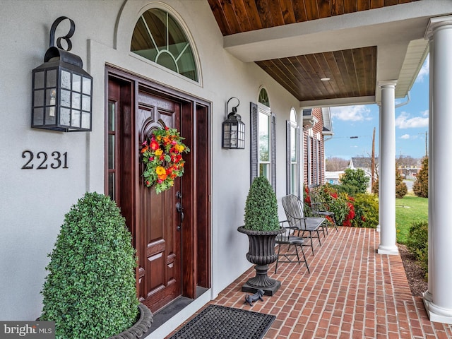 doorway to property featuring a porch and stucco siding