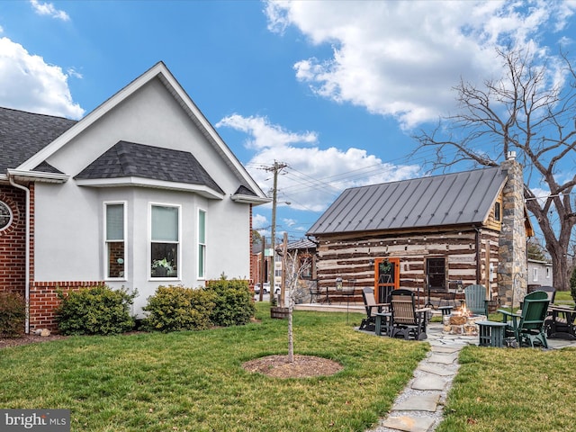 exterior space featuring an outdoor fire pit, a lawn, a chimney, roof with shingles, and stucco siding