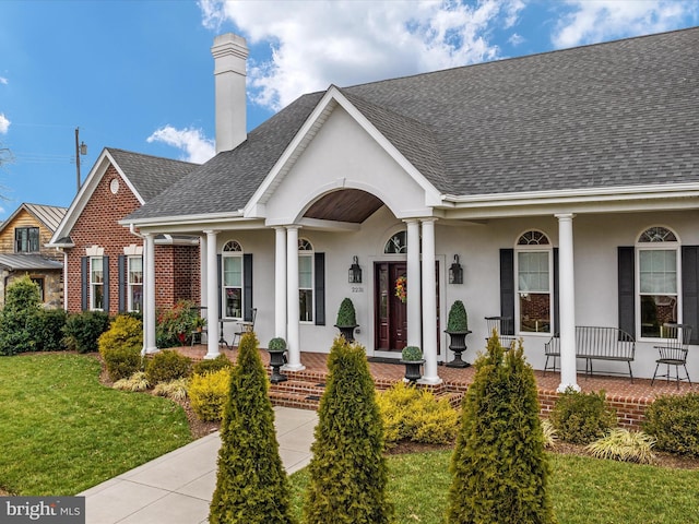 view of front of home with covered porch, roof with shingles, and stucco siding