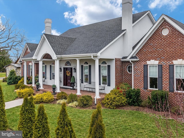 view of front of home featuring a front yard, stucco siding, a chimney, and brick siding