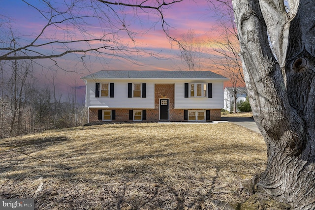 split foyer home featuring brick siding and a lawn