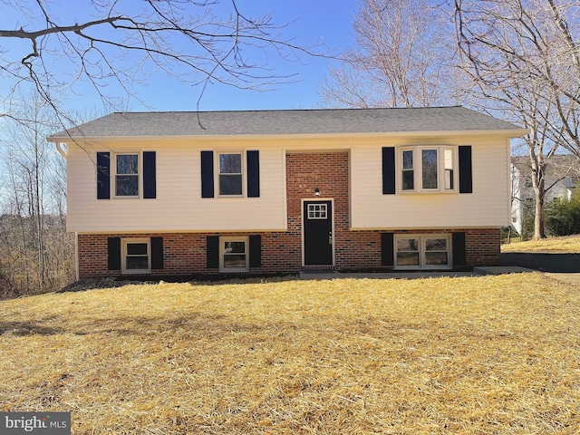 bi-level home with brick siding and a front lawn