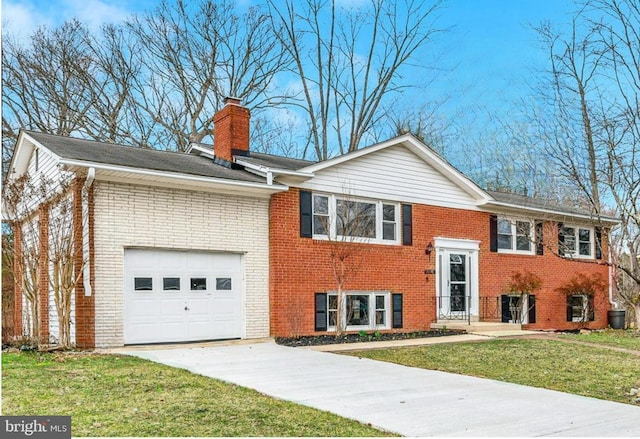 split foyer home with an attached garage, brick siding, a chimney, and a front yard