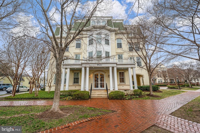 view of front facade with french doors, a porch, a balcony, and stucco siding