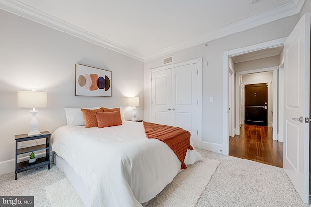 carpeted bedroom with a closet, visible vents, crown molding, and baseboards