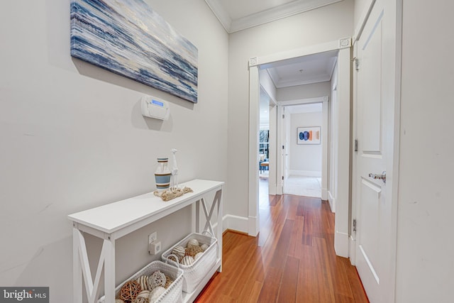 hallway featuring crown molding, baseboards, and wood finished floors