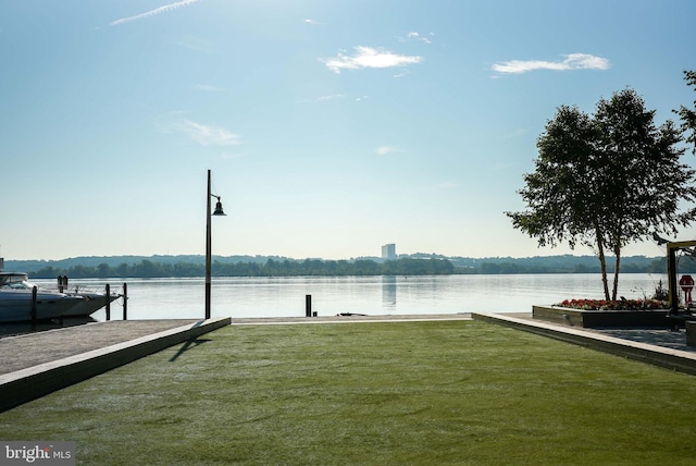 view of dock with a lawn and a water view