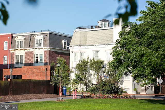 exterior space with a high end roof, mansard roof, and brick siding