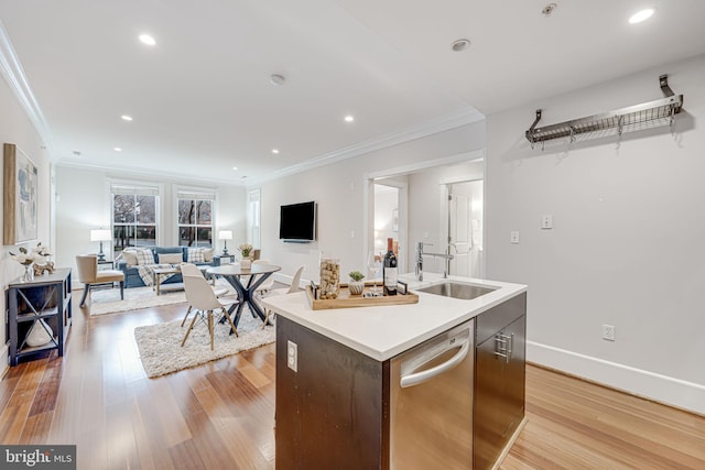 kitchen featuring light wood finished floors, a kitchen island with sink, crown molding, stainless steel dishwasher, and a sink