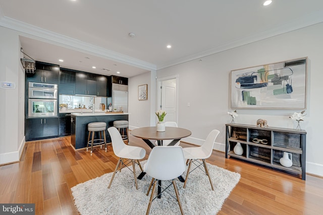 dining room featuring ornamental molding, light wood-style flooring, and baseboards