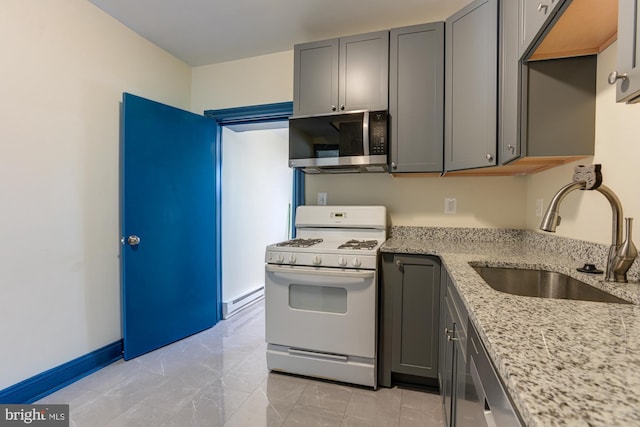 kitchen featuring gray cabinets, appliances with stainless steel finishes, a baseboard heating unit, a sink, and light stone countertops