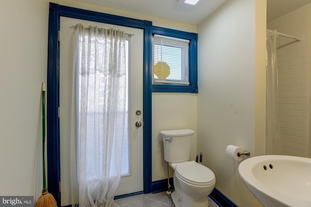 full bath with baseboards, a shower with shower curtain, toilet, tile patterned flooring, and a sink