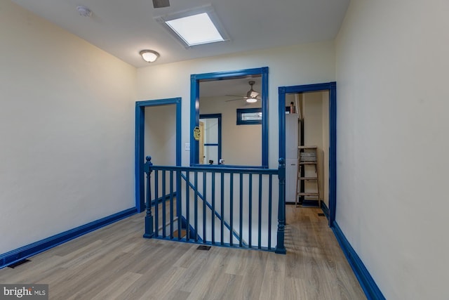 corridor featuring baseboards, visible vents, an upstairs landing, and wood finished floors