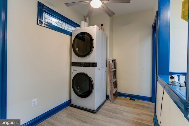 clothes washing area with a ceiling fan, stacked washer and clothes dryer, light wood-style flooring, and baseboards