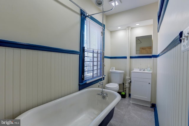 full bath featuring a freestanding tub, wainscoting, vanity, and toilet