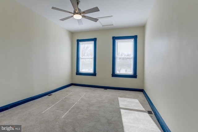 carpeted empty room featuring visible vents, a ceiling fan, attic access, and baseboards