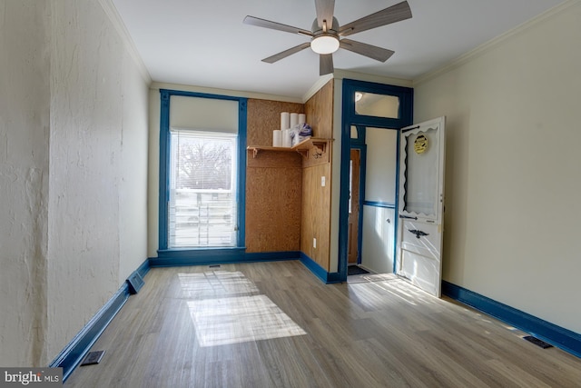 spare room with a ceiling fan, crown molding, baseboards, and wood finished floors