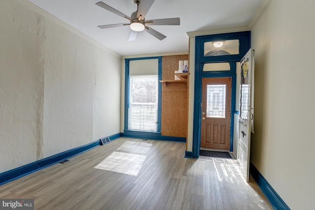 entrance foyer featuring a textured wall, baseboards, crown molding, and wood finished floors