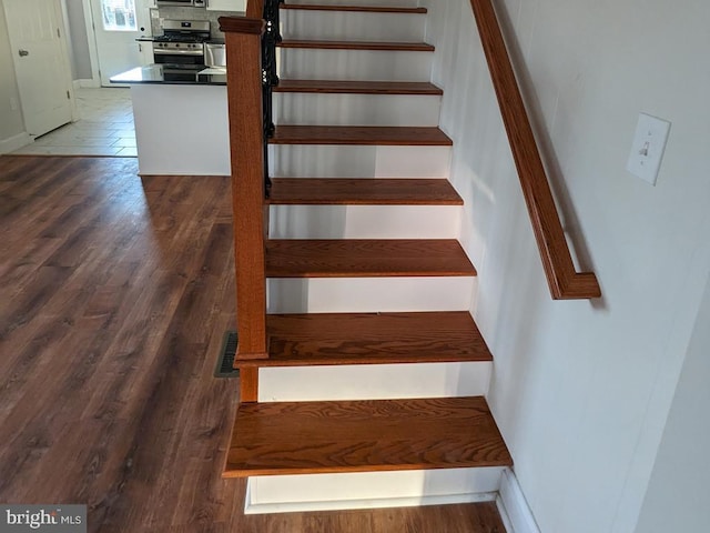 stairs featuring wood finished floors and baseboards