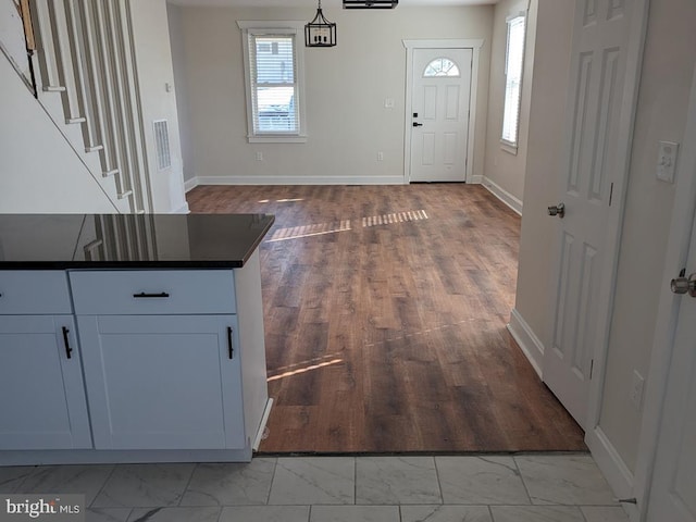 entrance foyer featuring marble finish floor, stairway, and baseboards