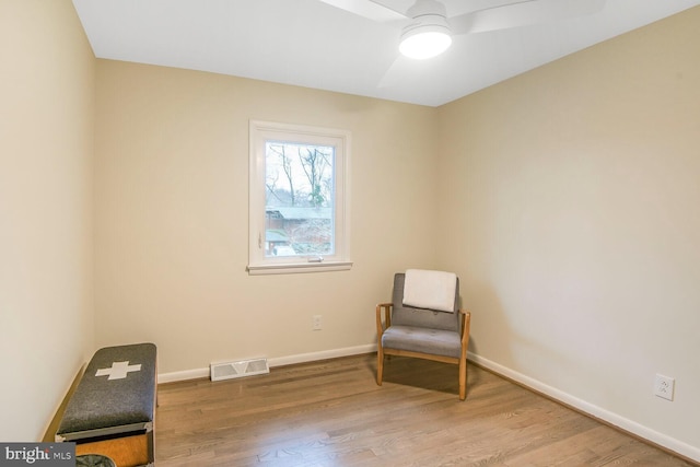 living area featuring a ceiling fan, baseboards, visible vents, and wood finished floors