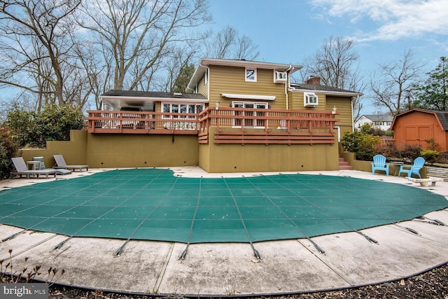 view of swimming pool with a covered pool, a patio, a deck, and a shed