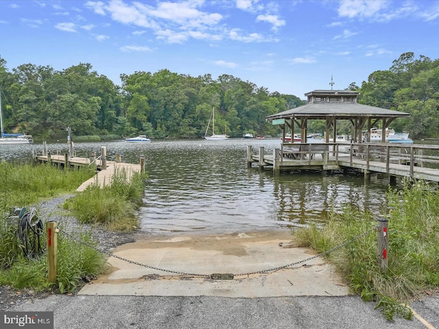 view of dock with a gazebo, a forest view, and a water view