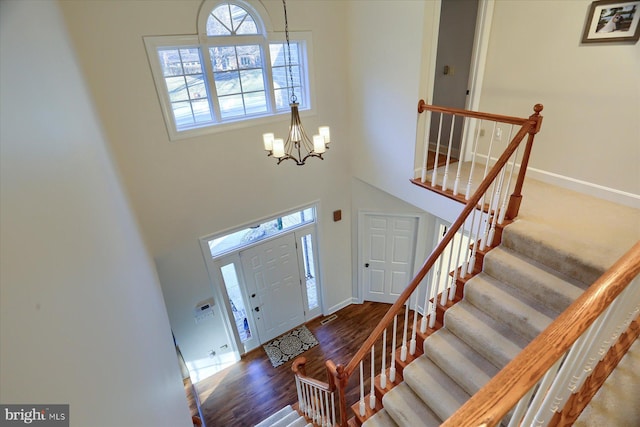 foyer with baseboards, a high ceiling, wood finished floors, and a notable chandelier