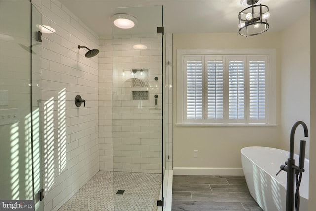 full bathroom featuring a stall shower, a soaking tub, wood finish floors, and baseboards