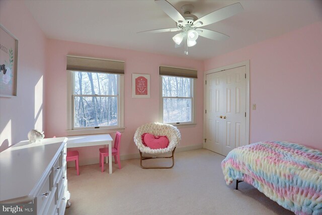 bedroom with baseboards, multiple windows, a ceiling fan, and light colored carpet