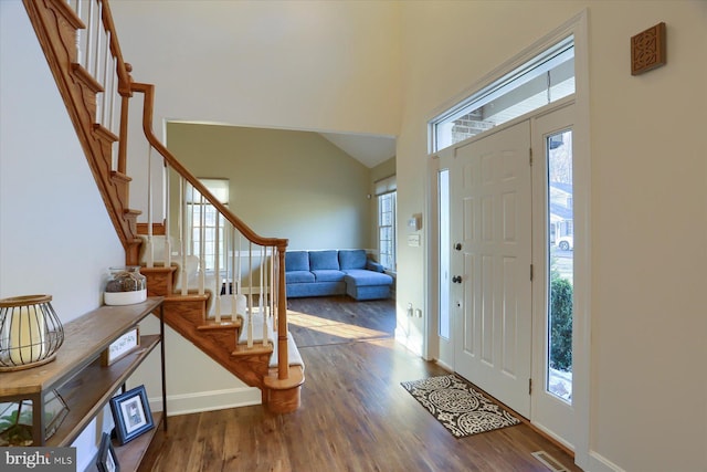 entrance foyer with a healthy amount of sunlight, stairway, a high ceiling, and wood finished floors