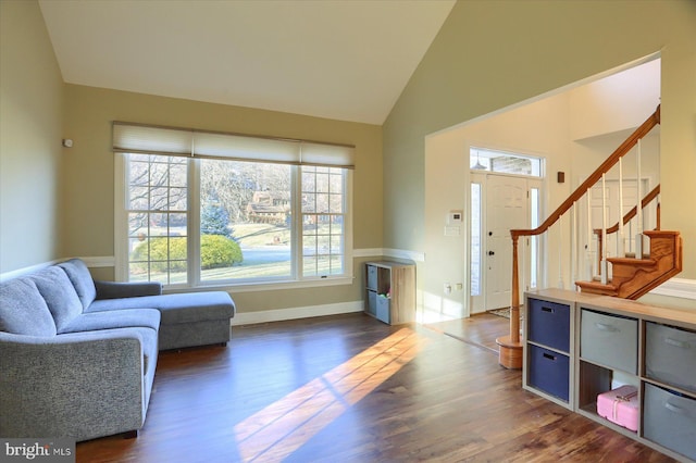 interior space featuring dark wood-type flooring, high vaulted ceiling, baseboards, and stairs