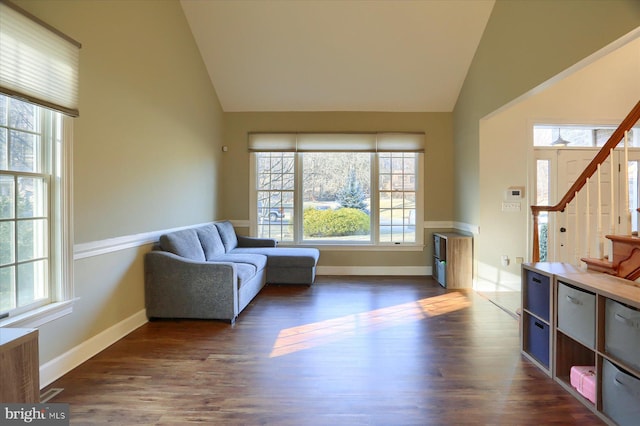 living area featuring high vaulted ceiling, dark wood-type flooring, stairway, and baseboards