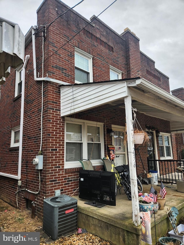 view of property exterior with cooling unit, covered porch, and brick siding