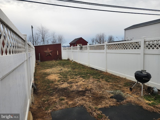 view of yard featuring a fenced backyard, an outdoor structure, and a storage shed