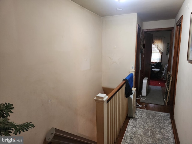 corridor with wood finished floors, an upstairs landing, and baseboards