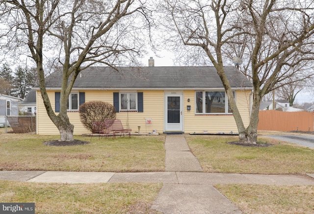 view of front facade featuring a front yard, fence, and a chimney