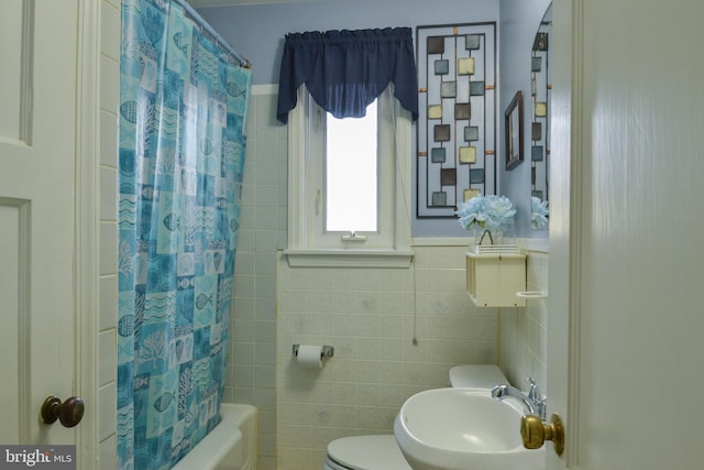 full bathroom featuring tile walls, toilet, shower / bath combo, wainscoting, and a sink