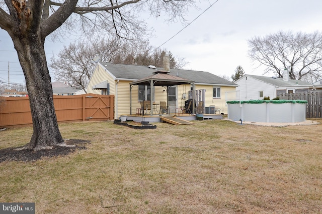 back of house featuring fence, a deck, a fenced in pool, and a gazebo