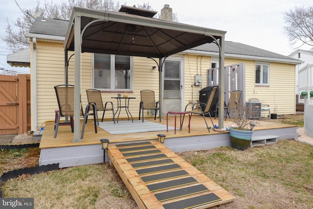 back of property with a gate, fence, a wooden deck, and a gazebo