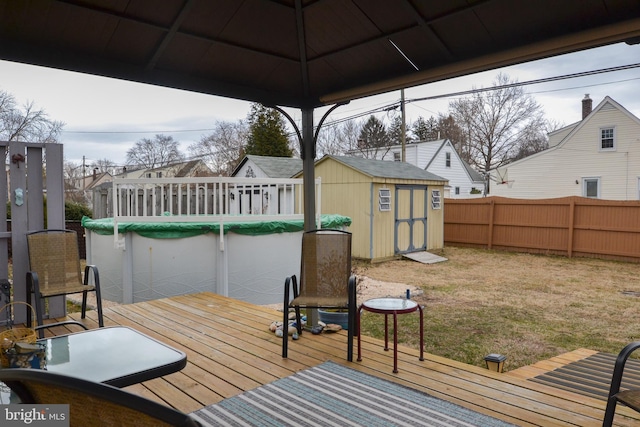 wooden deck with an outbuilding, fence, a residential view, and a storage unit